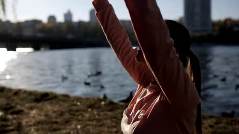 The-girl-on-the-promenade-in-yoga.-Backlight,-silhouette-against-the-city-buildings.