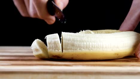 Man-is-cutting-banana-on-cutting-board-in-slow-motion