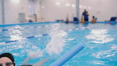 clases-de-natación-para-niños-en-la-piscina---hermosa-chica-de-piel-clara-nada-en-el-agua