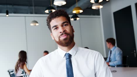 Portrait-Of-Businessman-In-Modern-Boardroom-With-Colleagues-Meeting-Around-Table-In-Background-Shot-In-Slow-Motion