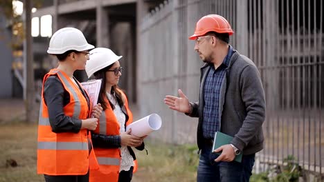 The-engineer-communicates-with-the-female-customer-representatives-at-the-construction-site,-checking-the-drawings-with-the-actual-progress-of-construction-work