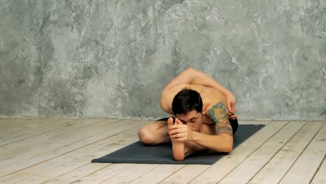 Man-practicing-yoga-in-half-hero-stretch-pose