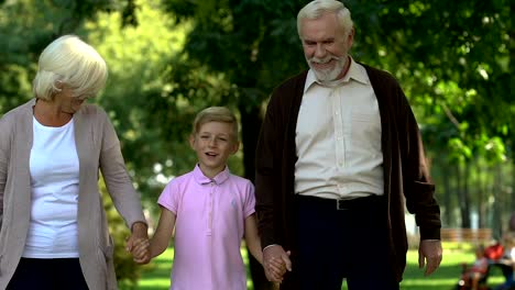 Little-boy-walking-with-his-grandparents-in-park,-enjoying-happy-time-together