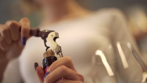 Chica-tira-el-corcho-de-una-botella-de-vino-con-un-sacacorchos-Close-up.-Una-chica-con-una-botella-de-manicura-hermosa-descorche-de-vino.