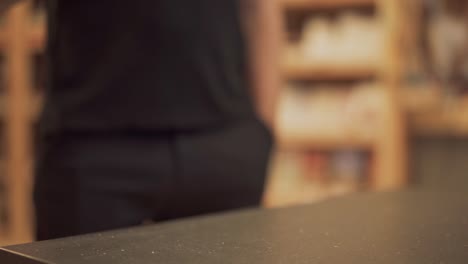 Male-hand-puts-glass-on-the-table-and-moves-it-closer-to-camera.-Almost-empty-glass-of-red-wine-is-on-the-desk-closeup