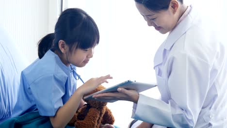 Médico-a-la-niña-en-el-Hospital,-la-niña-mirando-a-tablet-con-doctor-junto-en-el-hospital.-Personas-con-la-tecnología,-concepto-de-salud-y-médico.