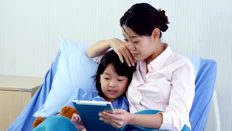 Niña-y-su-madre-usando-la-tableta-juntos-en-el-hospital.-Personas-con-tecnología,-familia,-concepto-de-salud-y-médico.