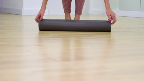 young-woman-feet-entering-gym,-unrolling-mat-in-slow-motion