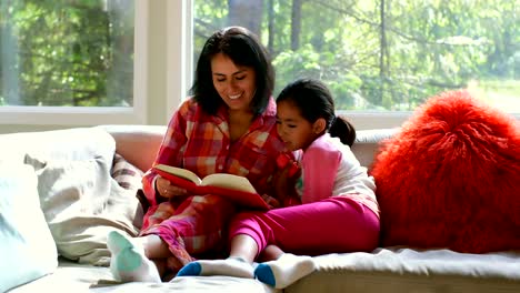 Mother-and-daughter-reading-book-in-living-room-4k