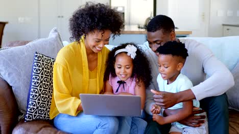 Vista-frontal-de-la-familia-black-utilizando-la-computadora-portátil-en-la-sala-en-página-4k