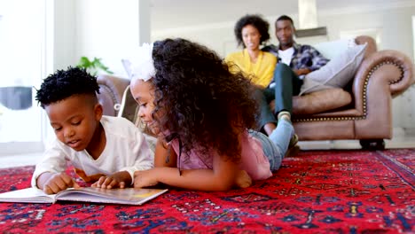 Front-view-of-cute-black-kids-reading-story-book-in-living-room-at-comfortable-home-4k