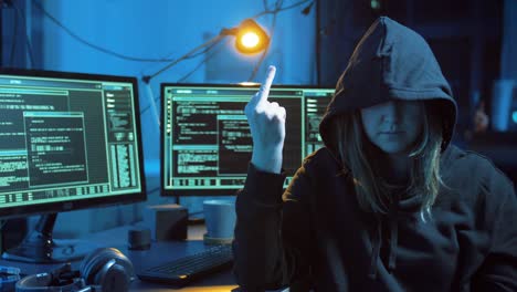 hacker-femenino-mostrando-el-dedo-medio-en-la-habitación-oscura