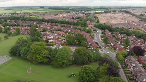 Aerial-footage-of-the-town-known-as-Crossgates-in-the-Leeds-area-of-West-Yorkshire-in-the-UK,-showing-a-typical-British-town-and-street-with-rows-of-houses-and-light-traffic-on-the-main-roads.