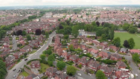 Aerial-footage-of-the-town-known-as-Crossgates-in-the-Leeds-area-of-West-Yorkshire-in-the-UK,-showing-a-typical-British-town-and-street-with-rows-of-houses-and-light-traffic-on-the-main-roads.