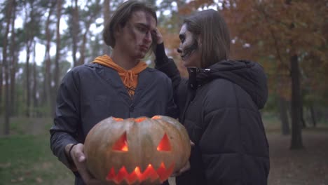 Mann-und-Frau-in-Halloween-Kostümen-mit-Make-up-suchen-in-die-Kamera-mit-ernsten-beängstigend-Gesichter-im-Herbst-park