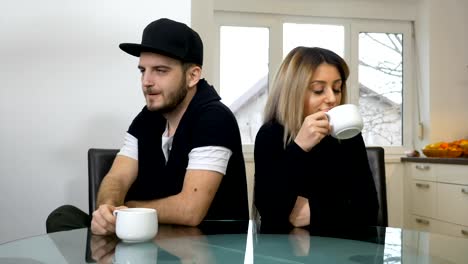 Upset-sad-couple-drinking-coffee-after-a-fight-sitting-in-the-kitchen-at-home