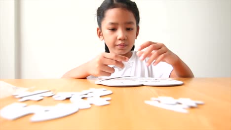 Asian-little-girl-playing-jigsaw-puzzle-select-focus-on-hand-shallow-depth-of-field