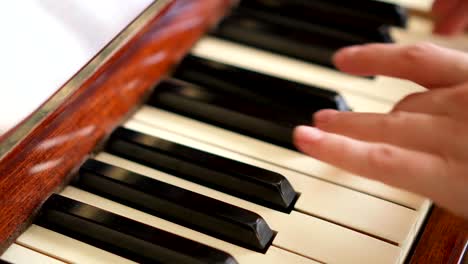 Female-fingers-playing-keys-on-retro-piano-keyboard.-Shallow-depth-of-field.-Focus-on-piano-keys