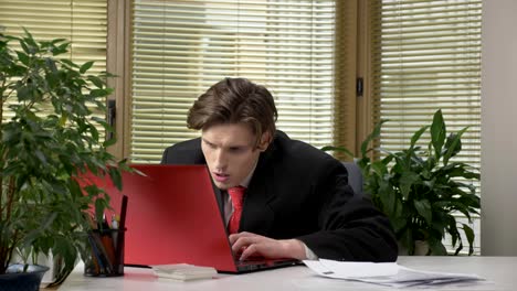 Young-guy-in-a-suit-is-sitting-at-the-office,-working-on-a-laptop,-tired,-falling-asleep,-bored.-60-fps