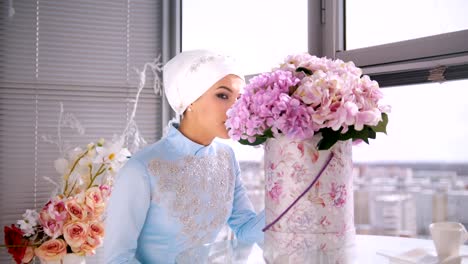 Hermosa-novia-musulmana-con-conforman-en-vestido-tradicional-azul-de-nikah-sentado-cerca-de-la-ventana