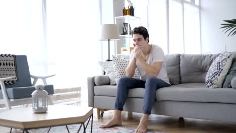 Upset-Young-Man-in-Tension-Sitting-on-Sofa-and-Thinking