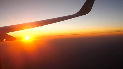 View-from-airplane-window-to-beautiful-sunrise-or-sunset.-Wing-of-plane-and-cloud-in-sky.-Concept-of-travel-or-tourism.-Close-up-Side-view