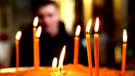 Burning-candles-in-the-foreground,-man-in-the-back-out-of-focus