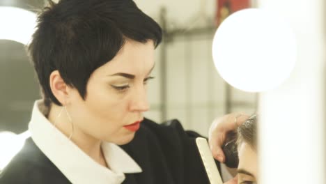 Frau,-männliche-Frisur-mit-elektrischen-Rasierapparat.-Friseur-Haare-schneiden-mit-Haarschneider-im-Friseurladen-hautnah.-Mann-Friseur-mit-Elektrorasierer