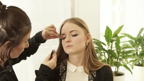 Woman-visagiste-using-cosmetics-sponge-for-makeup-correction-on-face-beautiful-woman-in-dressing-room.-Close-up-makeup-woman-face-in-beauty-studio