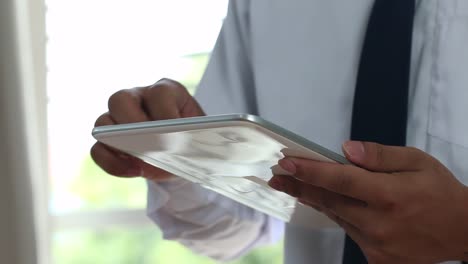 Online-searching-social-networks-by-Smartphone-Concept:-Businessman-stand-using-laptop-computer-device,-hands-typing-text-message-to-connect-WiFi-for-shopping-online-in-office-window.