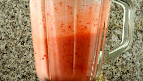 Preparation-of-cocktail-in-the-blender-from-apples,-bananas-and-strawberry.	Shooting-in-kitchen.