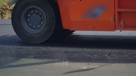 orange-steamroller-for-asphalt-with-four-wheels-stands-on-the-road-at-day