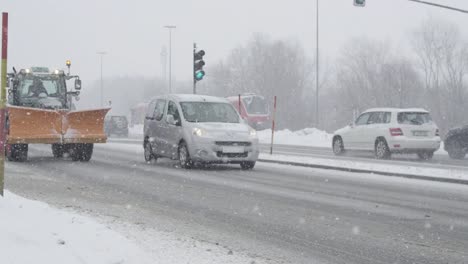 SLOW-MOTION:-Tractor-with-a-snow-plough-and-cars-drive-down-the-snowy-road.