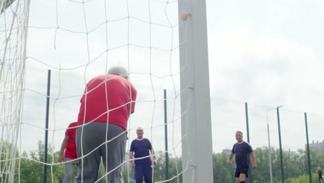 Senior,-fangend-Fußball-am-Ziel-Netto