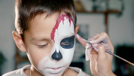 Make-up-artist-makes-the-boy-halloween-make-up.-Halloween-child-face-art.