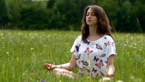 Female-meditating-outdoors-on-green-grass-in-summer,-sitting-lotus-concentration