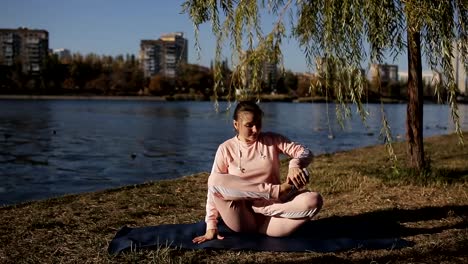 Chica-en-un-juego-de-los-deportes-en-un-yoga-de-río-en-el-fondo-del-paisaje-urbano.