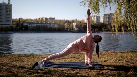 Yoga-en-el-paseo-de-la-metrópolis-moderna.-Chica-en-un-juego-de-los-deportes-en-un-yoga-de-río-en-la-estera.