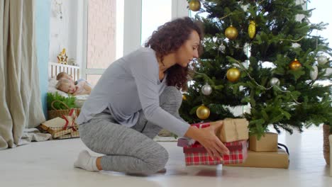 Madre-dejando-regalos-debajo-del-árbol-de-Navidad