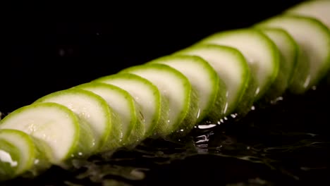 In-Scheiben-geschnittene-Zucchini-fallen-in-den-nassen-Tisch.-Slow-Motion-240-fps