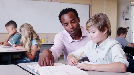 Male-elementary-school-teacher-working-in-class-with-boy