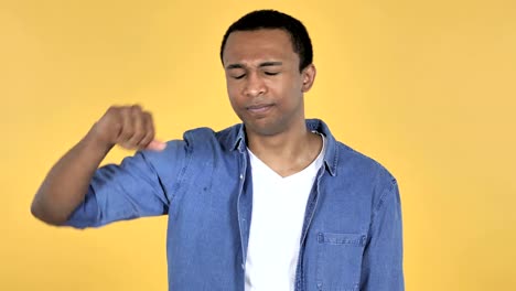 Young-African-Man-Gesturing-Thumbs-Down-Isolated-on-Yellow-Background