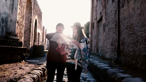 Happy-European-mother-and-daughter-with-a-map-exploring-historic-antique-streets-of-Pompeii,-Italy-on-a-vacation.