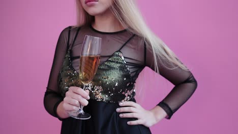 Hübsches-Mädchen-tragen-rote-Hörner,-halten-Sie-ein-Glas-Champagner-und-für-Kamera-im-Studio-rosa-Hintergrund-darstellen