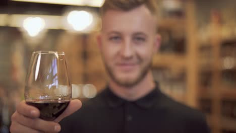 Gut-aussehender-Mann-heben-sein-Weinglas-Closeup-Portrait.-Der-Fokus-wechselt-aus-dem-Glas-Wein-zum-Kerl-und-zurück.