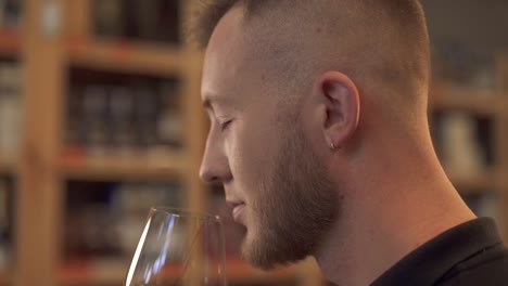 Portrait-of-handsome-male-sniffing-wine-in-the-glass-close-up-in-profile-Man-admires-alcohol-drink