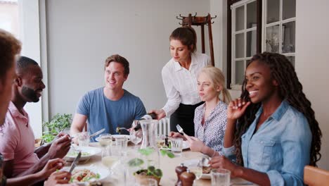 Camarera-que-sirve-vino-al-grupo-de-amigos-a-comer-en-el-restaurante