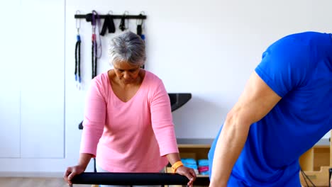 Entrenador-de-asistencia-a-senior-femenino-en-la-realización-de-yoga-4k