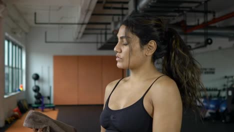 Beautiful-young-female-athlete-woman-wiping-sweat-after-intensive-exercise-workout-in-fitness-gym.-Shot-in-slow-motion