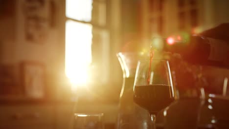 Man-Pouring-Red-Wine-Into-Glass-At-Kitchen-Table